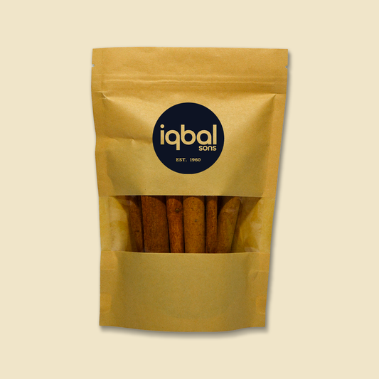 Kraft paper packaging with cinnamon sticks and 'iqbal sons' branding on a beige background